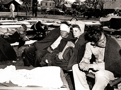 Injured survivors receive medical care following the 1947 Texas City Disaster, with hospital beds set up outdoors.