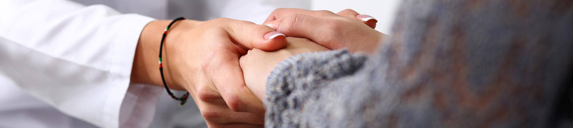 Close up of a doctor holding a patient's hand for comfort